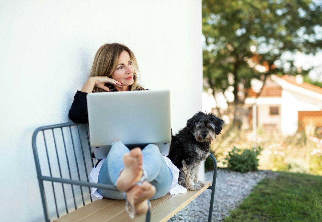 Frau mit Laptop und Hund draußen